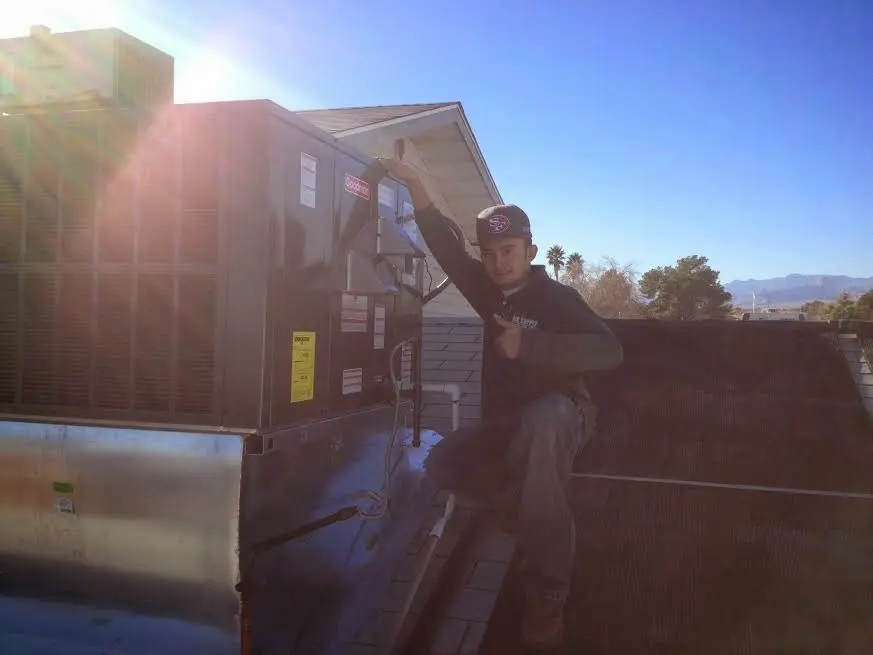 HVAC technician performing Heat Pump Repair on a rooftop unit in Leon Valley